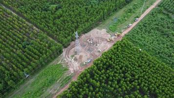 vista aérea de escavadeiras estão trabalhando nas fundações de postes de alta tensão e nas pernas de postes de alta tensão. vista superior da construção de linhas de energia na floresta. video