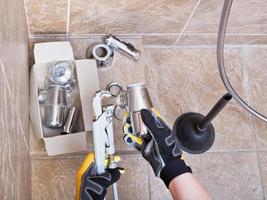 plumber repairs sink trap in bathroom photo