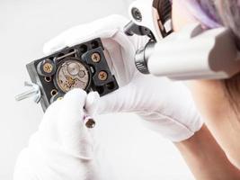 watchmaker in lenses repairs old wristwatch photo