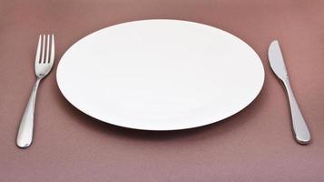 empty porcelain plate with fork and knife on brown photo