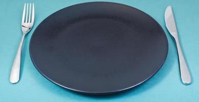 dinner black plate with fork and knife on green photo