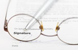 signature of contract and pen through eyeglasses photo