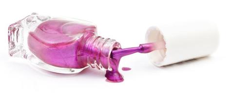 bottle and spilled purple nail polish on white photo