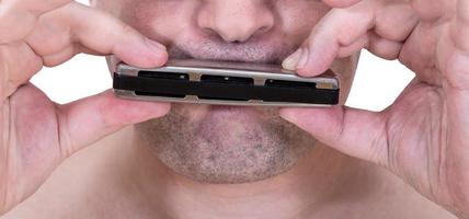 unshaven strolling musician playing harmonica photo