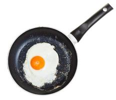 top view of one fried egg in black frypan isolated photo