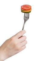 hand holding fork with fresh sliced vegetables photo