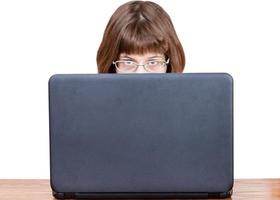 girl with spectacles looks over cover of laptop photo