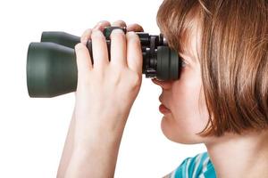 side view of girl looks through field glasses photo