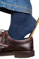 man dons brown shoes using shoe horn isolated photo