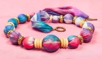 necklace from silk balls and bone rings on pink photo