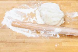 flour, rolling pin and kneading dough on table photo