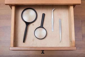 magnifying glasses and tweezers in open drawer photo