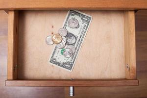 one US Dollar and coins in open drawer photo