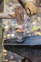 Blacksmith chops iron rod with hammer and chisel photo