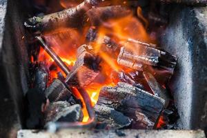 iron rod is heated in burning wooden coals photo
