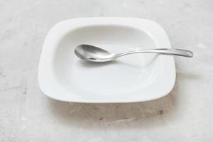 square white bowl with white spoon on concrete photo
