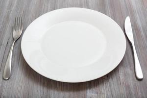 plato blanco, cuchillo, cuchara sobre mesa marrón gris foto