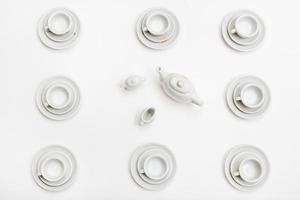 top view of cups with saucers and teapot on white photo