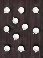 vista superior de muchas tazas blancas sobre una mesa de color marrón oscuro foto