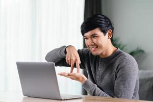 Young Asian man deaf disabled using laptop computer for online video conference call learning and communicating in sign language. photo