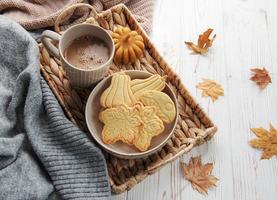 Cookies shaped like pumpkin and leaves on rustic wood background photo