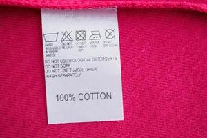 White laundry care washing instructions clothes label on red cotton shirt photo