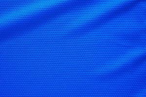 Blue football jersey clothing fabric texture sports wear background, close up top view photo