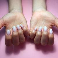 Manicure of different colors on nails. Female manicure on the hand on pink background photo