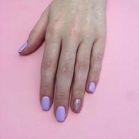Manicure of different colors on nails. Female manicure on the hand on pink background photo