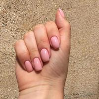 manos femeninas con elegante manicura rosa sobre fondo marrón foto