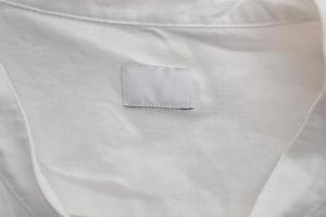 White blank clothing label on cotton shirt background photo