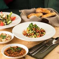 A close up shot of salads and appetizers near basket of breads photo