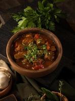 A close up shot of a meat stew and herbs in the background photo