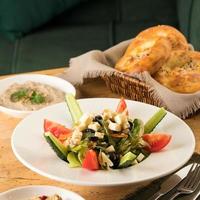 A close up shot of a salad and appetizers near basket of breads photo