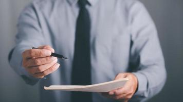 Businessman pointing at documents and sending pens to customers for signatures, document concepts contract agreement, employment, acceptance and approval in business, legal document handling photo