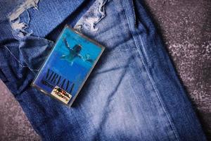 WASHINGTON, USA - September 30 2022  Nirvana's cassette tape and Ripped jeans or Torn jeans. A symbol of the grunge or Seattle sound. photo