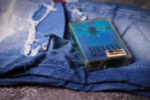 WASHINGTON, USA - September 30 2022  Nirvana's cassette tape and Ripped jeans or Torn jeans. A symbol of the grunge or Seattle sound. photo