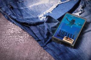 WASHINGTON, USA - September 30 2022  Nirvana's cassette tape and Ripped jeans or Torn jeans. A symbol of the grunge or Seattle sound. photo