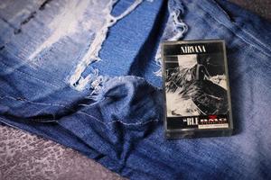 WASHINGTON, USA - September 30 2022  Nirvana's cassette tape and Ripped jeans or Torn jeans. A symbol of the grunge or Seattle sound. photo