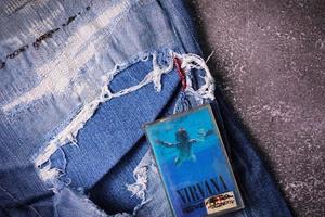 WASHINGTON, USA - September 30 2022  Nirvana's cassette tape and Ripped jeans or Torn jeans. A symbol of the grunge or Seattle sound. photo