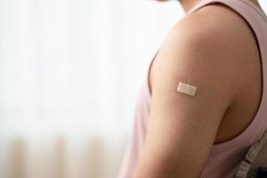 hombre con vendaje que muestra su brazo después de recibir la vacuna. foto