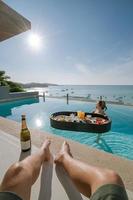 Boyfriend leg with girlfriend relax with floating breakfast in swimming pool villa hotel resort.