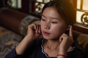 Closeup shot of an Asian girl is listening music song with enjoy and relax on the sofa in the house from smartphone, entertainment and rest concept photo