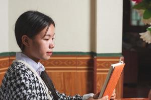 un joven estudiante está leyendo un libro escolar para aprender y prepararse para el examen y la tarea en la mesa, concepto de educación y estudio, espacio de copia de tiro trasero para texto individual foto