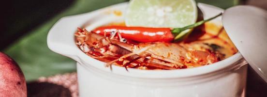 Tom Yum with Shrimp and River Shrimp With spices and chili in a cup placed on a wooden table photo