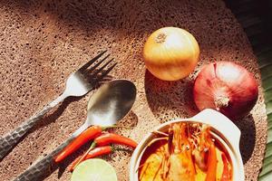 Tom Yum with Shrimp and River Shrimp With spices and chili in a cup placed on a wooden table photo