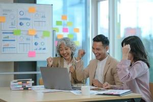 grupo de jóvenes empresarios asiáticos del equipo de negocios creativos compañeros de trabajo en el cargo felices de tener éxito en el trabajo en equipo de la asociación celebrando el logro y el concepto de éxito. foto