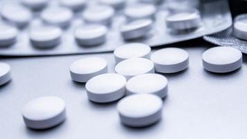 White medical pills are spread on the gray table. photo