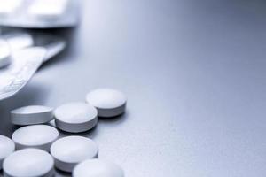 las píldoras médicas blancas se extienden sobre la mesa gris. foto