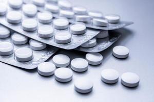 las píldoras médicas blancas se extienden sobre la mesa gris. foto